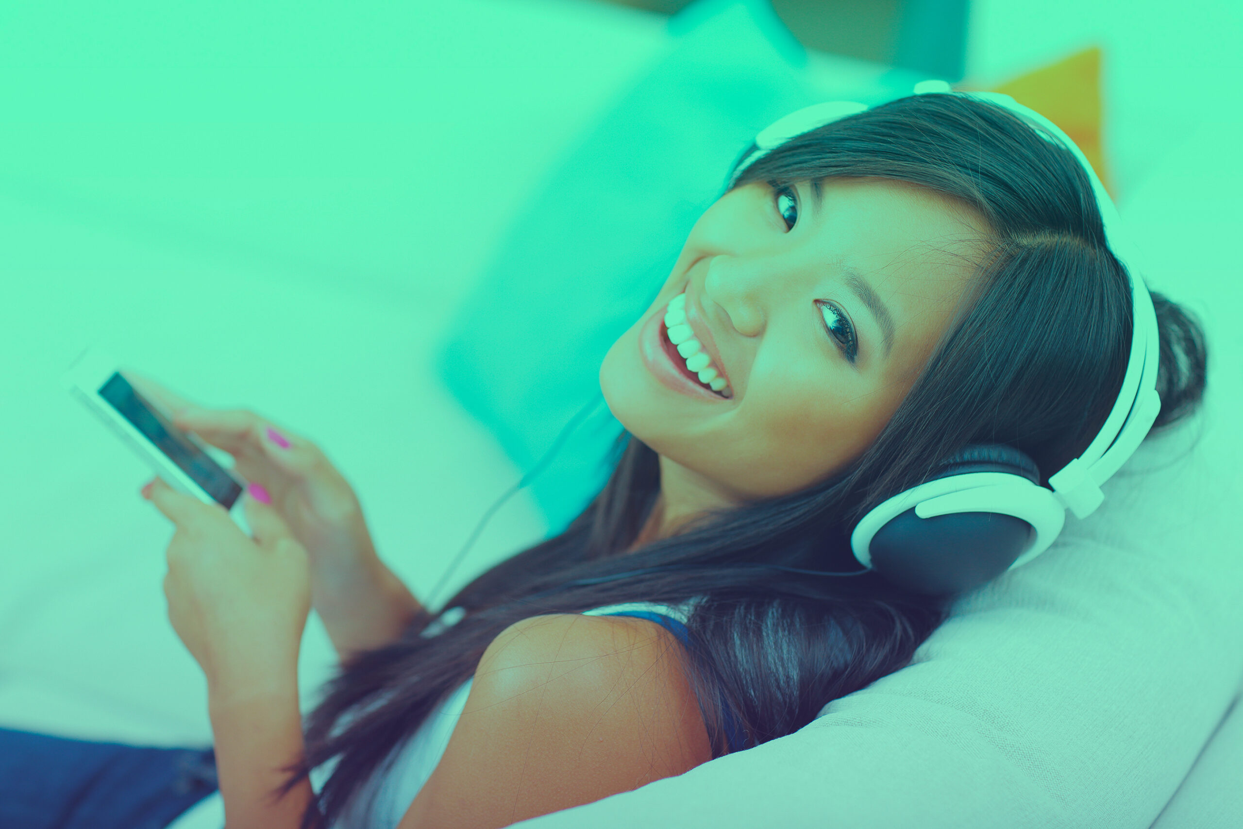 Closeup portrait of a young asian woman in headphones listening to music with her smartphone