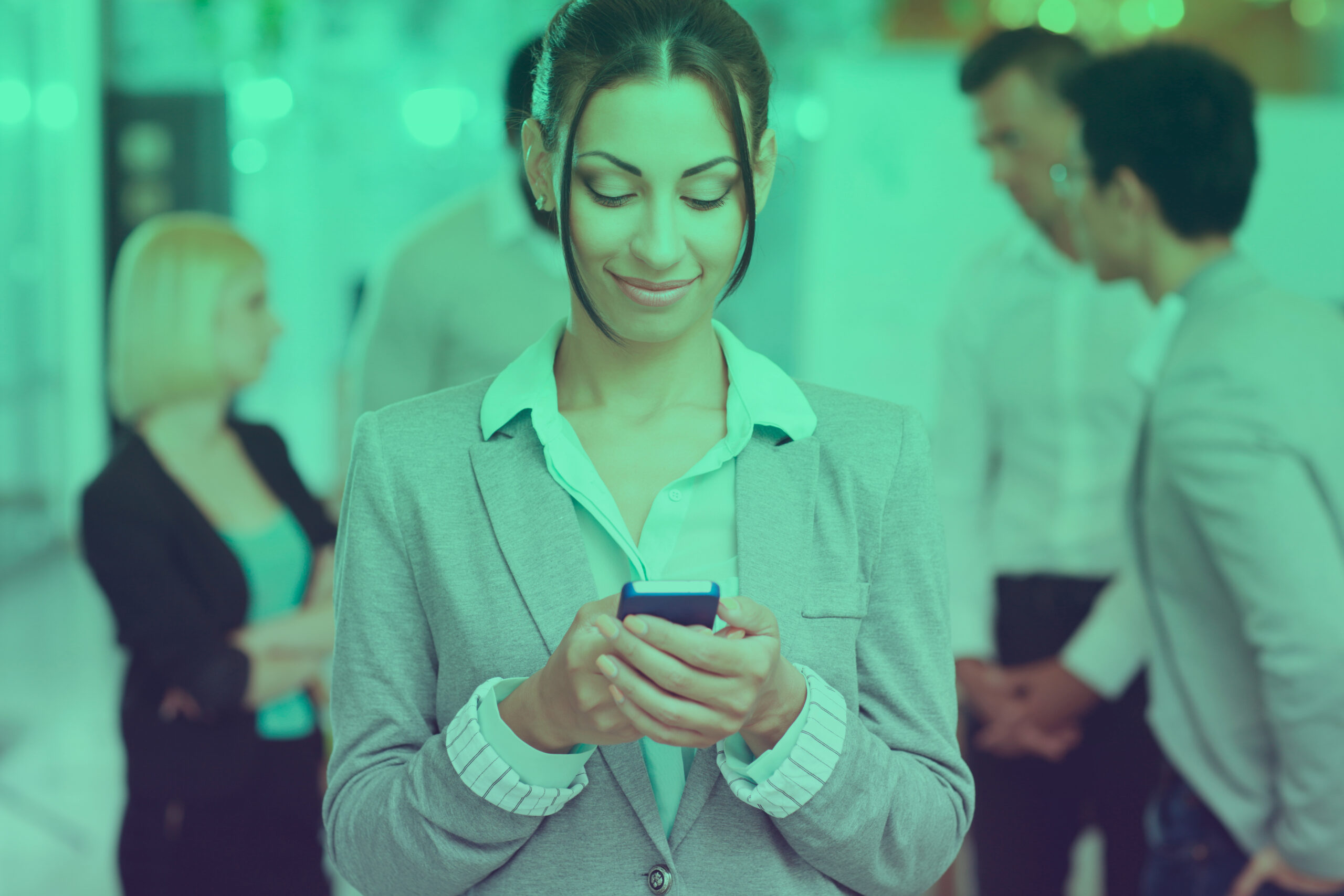 Portrait of a happy businesswoman using smartphone in front of colleagues
